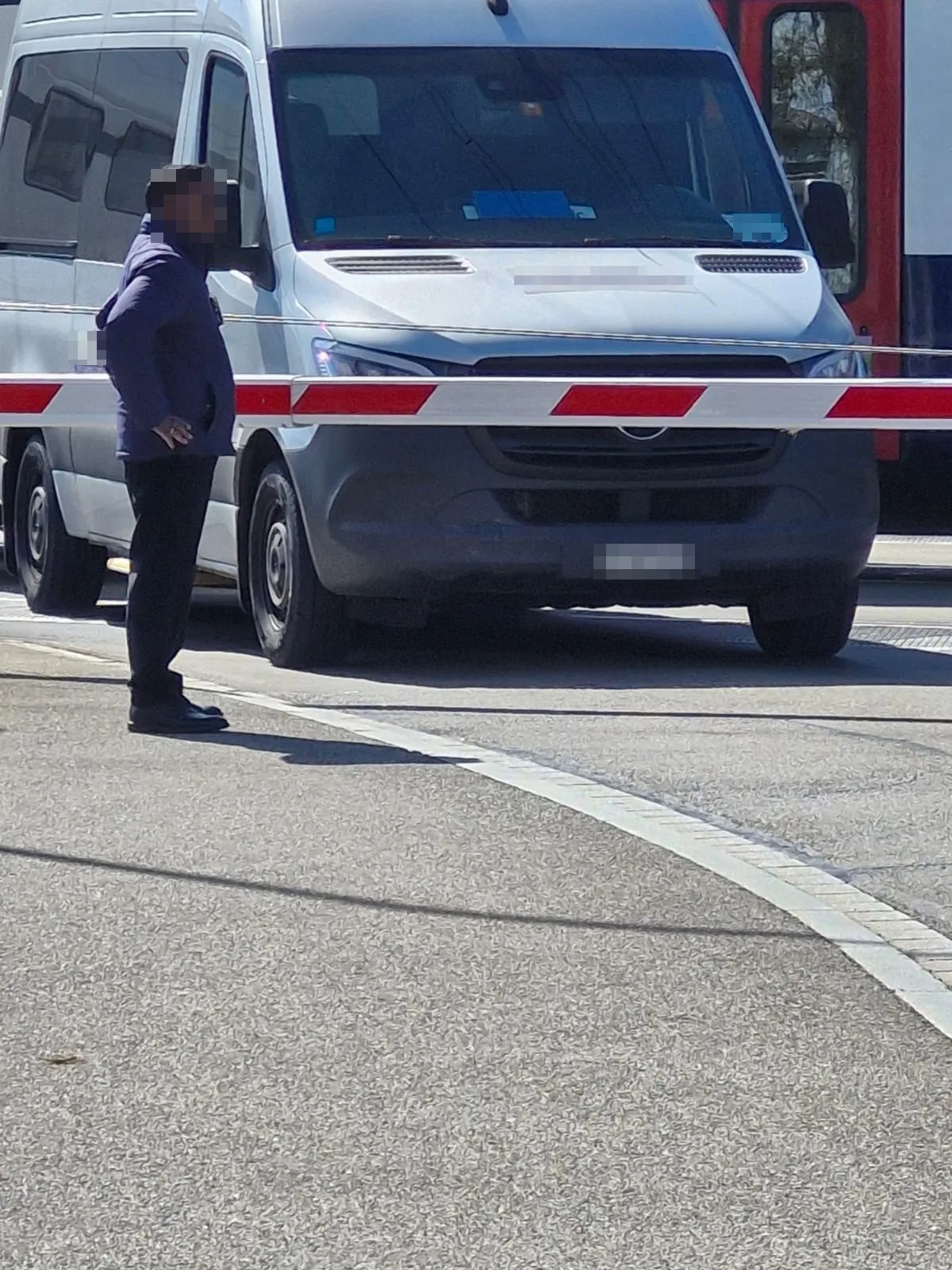 Ein Lieferwagen steht hinter einer geschlossenen Bahnschranke.